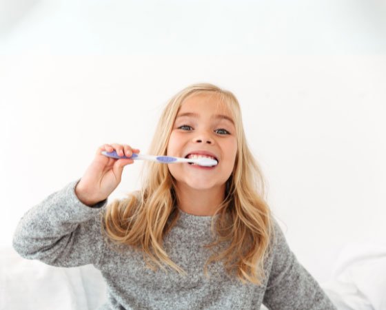 Nena somrient rentant-se les dents amb raspall de dents a la Cl&iacute;nica Dental Ariadna Barrachina d'Arenys de Munt